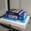 Stack of white and blue hardcover coffee table books. 