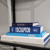 Stack of white and blue hardcover coffee table books. 
