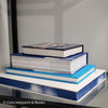 Stack of white and blue hardcover coffee table books. 