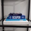 Stack of white and blue hardcover coffee table books. 