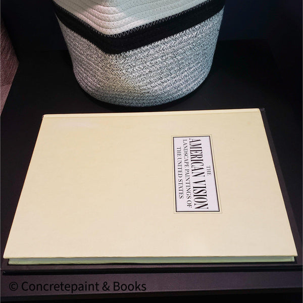 Large cream coffee table book stacked on  large black coffee table book.