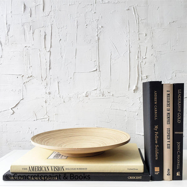 Real black and neutral headcover books used as staged home décor. Large coffee table books black and neutral with ikea bamboo bowl on top.